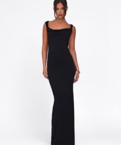 In a sleek Morana Dress by Tigermist, they pose confidently. The black dress features a long, elegant bodycon fit with thick shoulder straps. Their dark hair is neatly styled, and a bracelet adorns their right wrist, set against a plain white background.